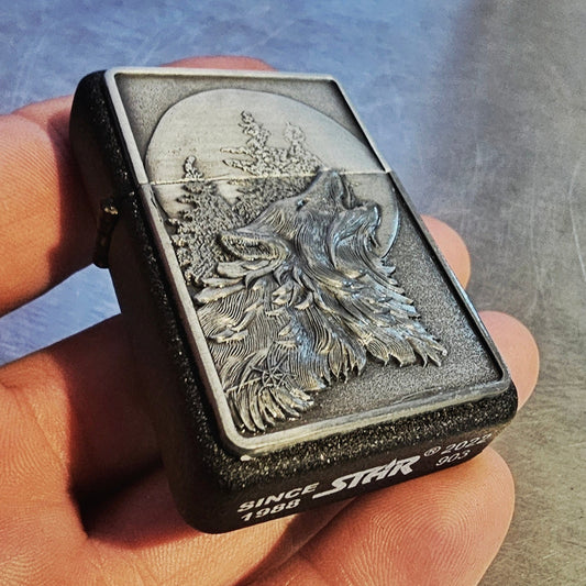 Hand holding a Flip lighter with a wolf design on a textured surface