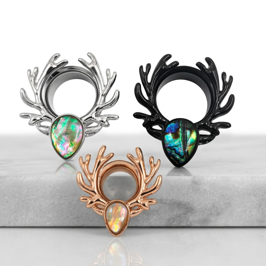 Three different coloured antler ear tunnels with gemstones on a reflective surface.