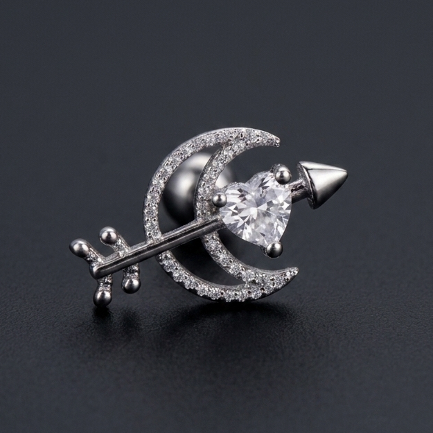 silver moon and heart arrow ear stud made of surgical steel, isolated on a grey background.
