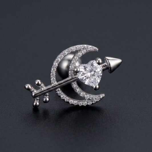 silver moon and heart arrow ear stud made of surgical steel, isolated on a grey background.
