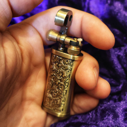 Hand holding a decorative lighter against a purple fabric background