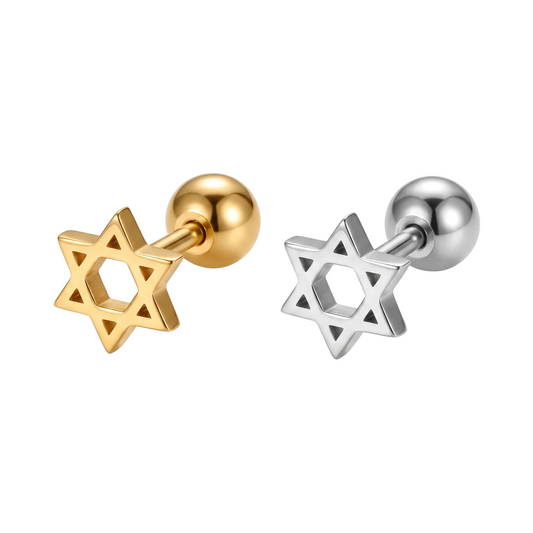 Two small star-shaped stud earrings shown side by side on a white background, one in polished yellow gold and one in polished silver, each with a round ball post. A blurred glittery band appears along the bottom edge.